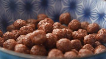 close up of chocolate corn flakes in a bowl on table . video