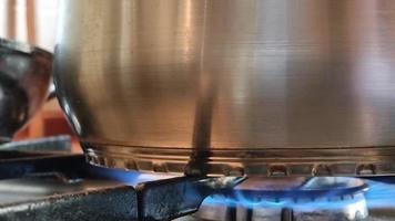 gros plan d'une casserole en acier inoxydable en feu. cuisiner des aliments sur une cuisinière à gaz. video