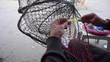 pescador conserta rede de armadilha de peixe dobrável na marinha