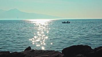 barco de pesca flotando en la orilla del mar por la tarde con brillo solar video