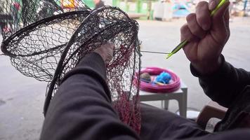 El pescador repara la red plegable de la trampa de peces en el mar video