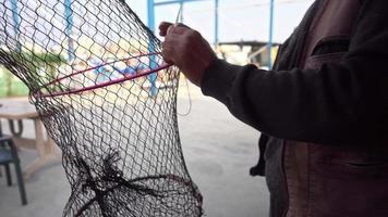 il pescatore ripara la rete pieghevole della trappola per pesci nel mare video
