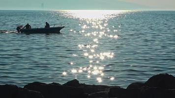 barco de pesca flotando en la orilla del mar por la tarde con brillo solar video