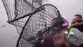 El pescador repara la red plegable de la trampa de peces en el mar video