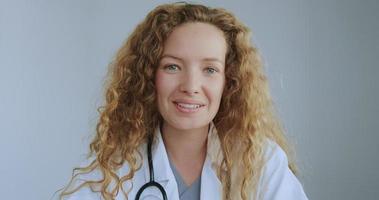 Female doctor waving hand and talking on video call in online medical meeting