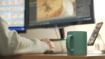 fotógrafo retocando fotos, trabajando en casa con una taza de café humeante