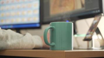 photographe retouchant des photos, travaillant à la maison avec une tasse de café fumant video