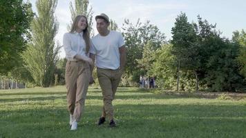 jeune couple marchant dans un parc public. heureux homme latin et femme caucasienne amoureuse