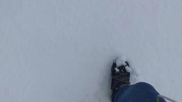 marcher dans la neige. femme randonnée dans la neige profonde en hiver dans la nature. pieds d'un homme marchant dans la neige avec des empreintes de pas un jour de neige.