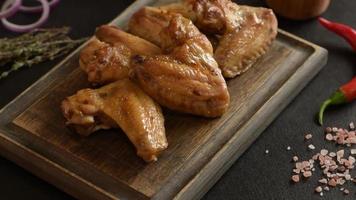 Baked chicken wings with vegetables and spices on a black background video