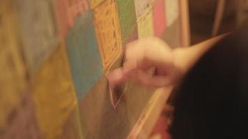 Närbild av den lilla flickans handkreativitet som ritar konstfärgen på svarta tavlan i barns fritidsutbildning med färgglada krita, rosa, gula, gröna, blå och happiness designillustrationer. video