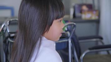 une petite fille asiatique se fait couper les cheveux dans un salon de beauté par un coiffeur. le coiffeur fait des coiffures pour de jolies petites filles. jolie petite fille coupant une frange. video