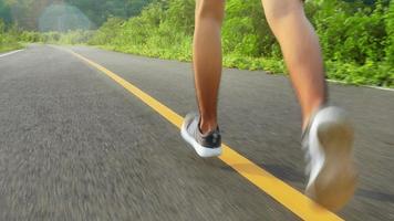 corridore di ragazzi adolescenti che corre sul sentiero stradale in allenamento mattutino per maratona e fitness. concetto di stile di vita sano. atleta in esecuzione che si esercita all'aperto. primo piano delle gambe. video