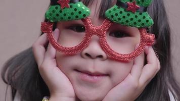 retrato de menina adorável em um óculos de natal engraçado em casa. feliz Natal e Feliz Ano Novo. video