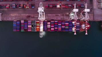 Luftbild-Zeitraffer des Frachtcontainerschiffs im internationalen Frachthafen unter dem Kranladetank für den Exportfrachtversand per Schiff. video