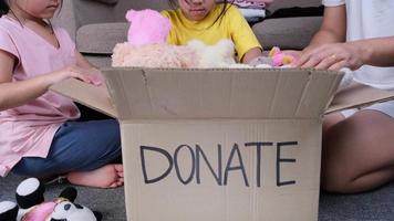 dos encantadoras hermanas con su madre poniendo su ropa en una caja de donaciones en casa para ayudar a los pobres. concepto de donación. video