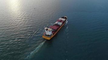 antenne van slim vrachtschip met container en rennen voor exportgoederen van vrachtwerfhaven naar ander oceaanconcept vrachtschip op blauwe hemelachtergrond. video