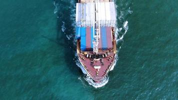 Antenne eines intelligenten Frachtschiffs, das Container trägt und für Exportgüter vom Frachthafen zu einem anderen Ozeankonzept-Frachtschiff auf blauem Himmelshintergrund läuft.