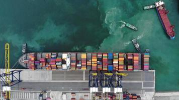 Aerial view timelapse of cargo container ship at the cargo international yard port under crane loading tank for export freight shipping by ship.