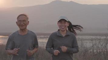 farfar och barnbarn joggar vid sjön i solnedgången och berättar historier om tidigare livsupplevelser. hälsosam livsstil koncept.
