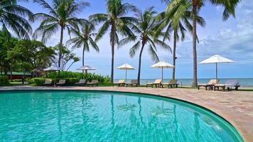 hermosa sombrilla y silla alrededor de la piscina en el hotel y resort - concepto de vacaciones video