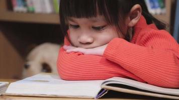 schattig klein meisje leest een boek. klein schattig Aziatisch meisje dat thuis studeert en geïnteresseerd is in leren. thuisonderwijs concept video