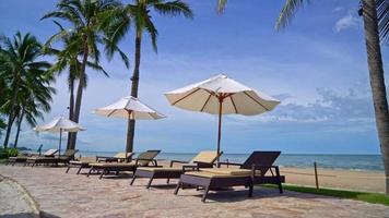 sombrilla y silla de playa con palmeras de coco y fondo de playa y cielo azul - vacaciones y vacaciones