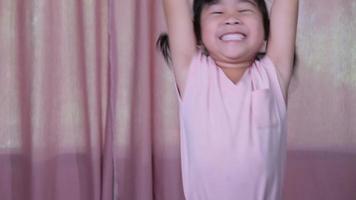 retrato de una linda niña con un vestido rosa saltando alegremente en casa. las chicas activas sienten libertad. concepto de expresiones faciales y gestos