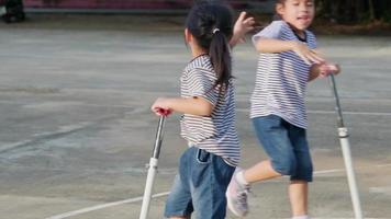 Zwei süße kleine Mädchen, die am Sommertag im Freien auf der Straße im Park Roller fahren. Kinder spielen draußen mit Rollern. aktive freizeit und outdoor-sport für kinder