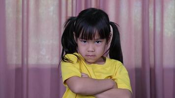 wütendes kleines asiatisches mädchen im gelben t-shirt, das zu hause enttäuschung und konflikte zeigt. das konzept der gesichtsausdrücke und gesten video