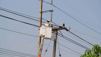 Electrician worker in lift bucket working on an electric pole to install and repair wires. video
