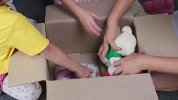 dos encantadoras hermanas con su madre poniendo su ropa en una caja de donaciones en casa para ayudar a los pobres. concepto de donación. video