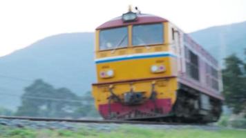 Diesel locomotives run on tracks to stop at the Lamphun Railway Station. This shot was filmed at Tha Chomphu White Bridge during sunset. video