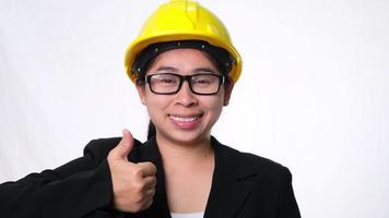 mujer técnica sonriendo con casco y mostrando los pulgares hacia arriba. mujer segura de sí misma trabajadora de la construcción sobre fondo blanco en el estudio. video