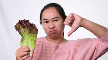 aziatische vrouw heeft een hekel aan verse salade op een witte achtergrond in de studio. dieet en gezond voedselconcept. video