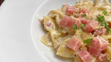 carbonara farfelle pasta with ham sausage on white plate video