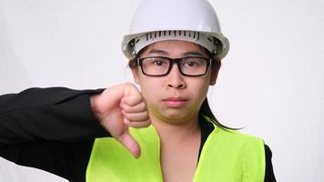 Female engineer in a helmet showing thumbs down, disapproving on white background in studio. video