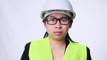 An angry female engineer in a helmet stands on a white background in a studio. stressed woman at work video