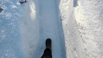 los pies caminan en la nieve. camino en el jardín despejado de nieve. video