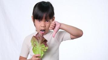 les enfants n'aiment pas manger de légumes. petite fille qui déteste manger de la salade verte. video