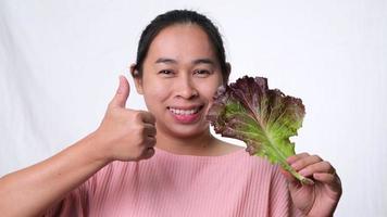 gezonde Aziatische vrouw met frisse salade duimen opdagen op een witte achtergrond in de studio. dieet en gezond voedselconcept. video