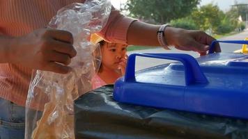 een Aziatische moeder en haar dochter gooiden een snackzakje bij het huisvuil. het concept van afvalscheiding en milieubescherming. video