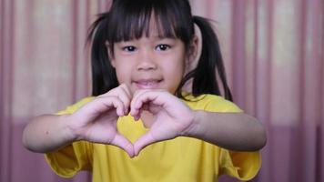 jolie petite fille faisant des gestes cardiaques avec les mains montrant l'amour et les soins. fille souriante en bonne santé montrant le symbole de l'amour.