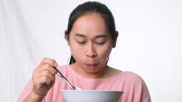 Asian woman eating cereales with milk on white background in studio. Woman having breakfast. Healthy breakfast concept