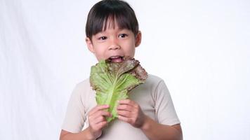 niña feliz con ensalada fresca mostrando los pulgares hacia arriba sobre fondo blanco en el estudio. buen hábito saludable para los niños. concepto de salud video