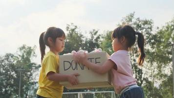 junge Freiwillige, die dem Empfänger im Park eine Spendenbox überreichen. Spendenkonzept. video