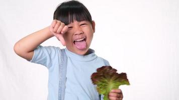 kinderen houden niet van groenten. klein meisje dat een hekel heeft aan het eten van groene salade. video