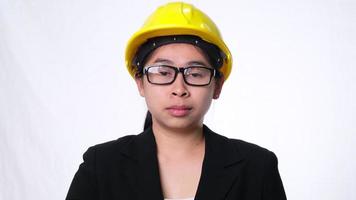 Female technician in helmet standing thumbs down, showing disapproval on white background in studio. video