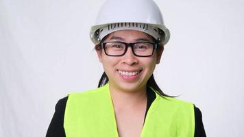 Smiling and confident female engineer wearing a helmet with her arms crossed over a white background in the studio.