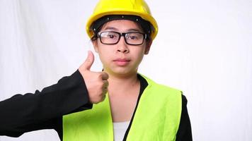 Woman technician smiling with helmet and showing thumbs up. Confident woman construction worker on white background in studio. video